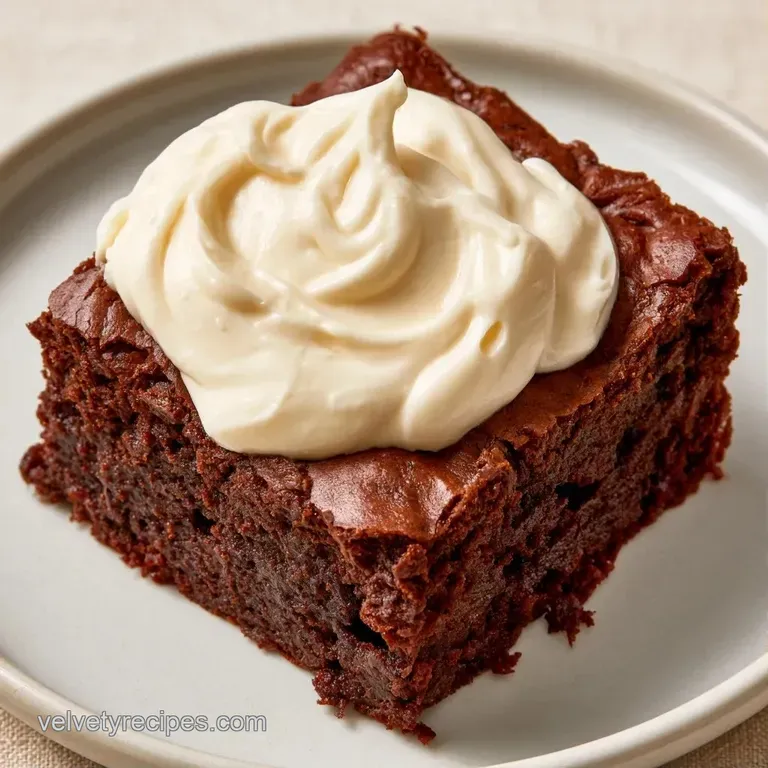 A neat square of rich chocolate and cream layers on a white ceramic plate with a dusting of powdered sugar.